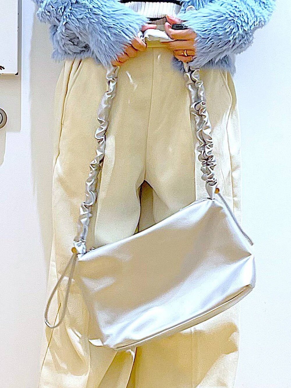 シルバー系のショルダーバッグ、ベージュ系のブーツ、ホワイト系のニット/セーターを着用したレディースの冬コーディネートの9枚目の写真