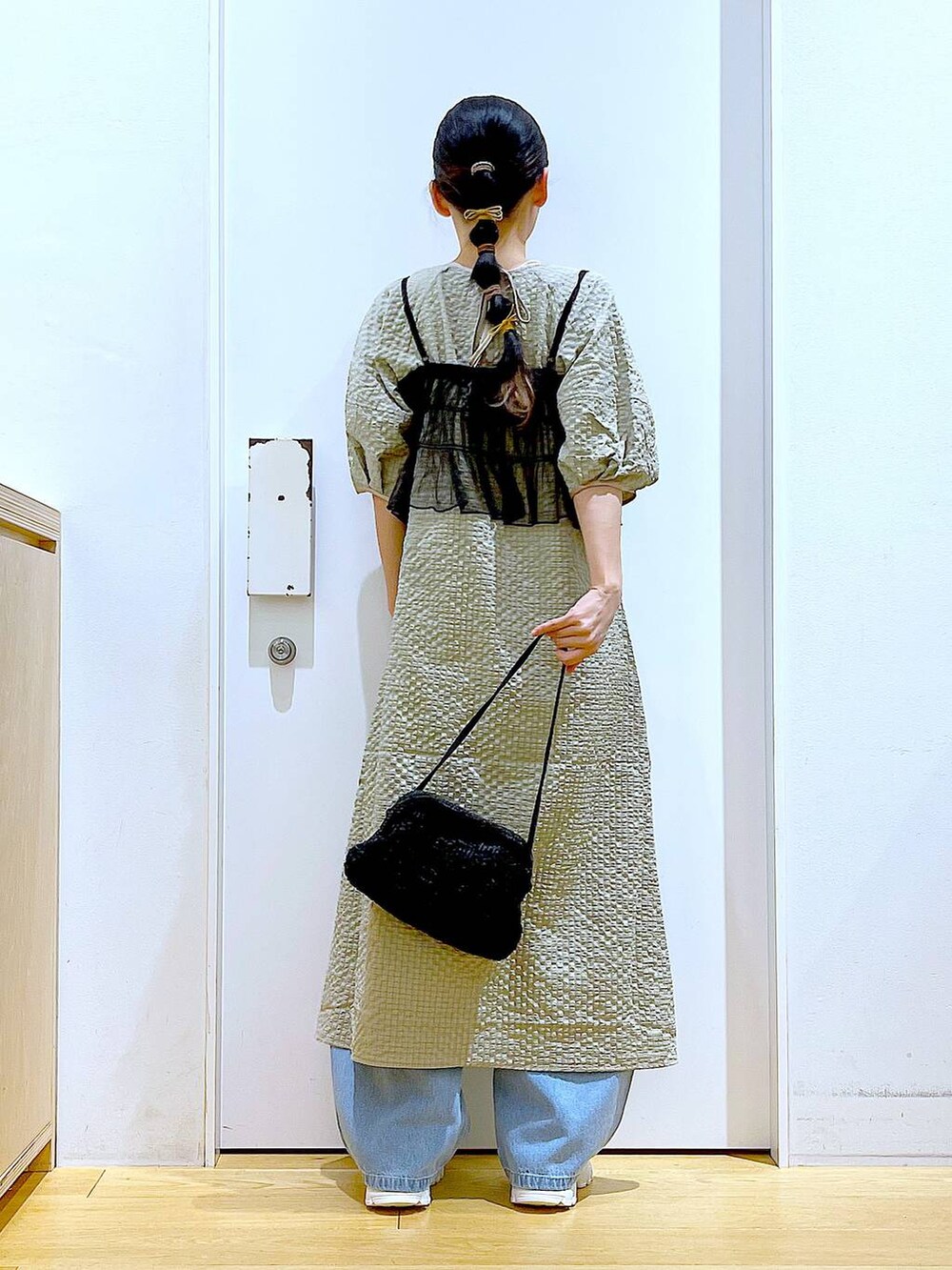 ホワイト系のスニーカー、ブルー系のデニムパンツ、ブラック系のショルダーバッグを着用したレディースの春コーディネートの5枚目の写真