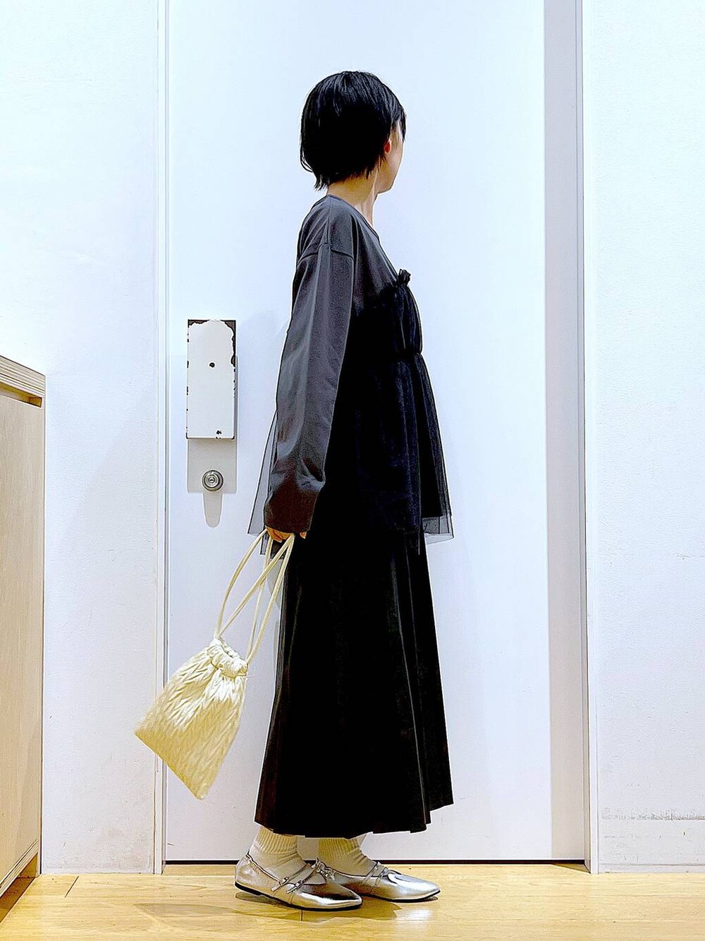 ホワイト系のショルダーバッグ、シルバー系のパンプス、ブラック系のスカートを着用したレディースの秋コーディネートの4枚目の写真