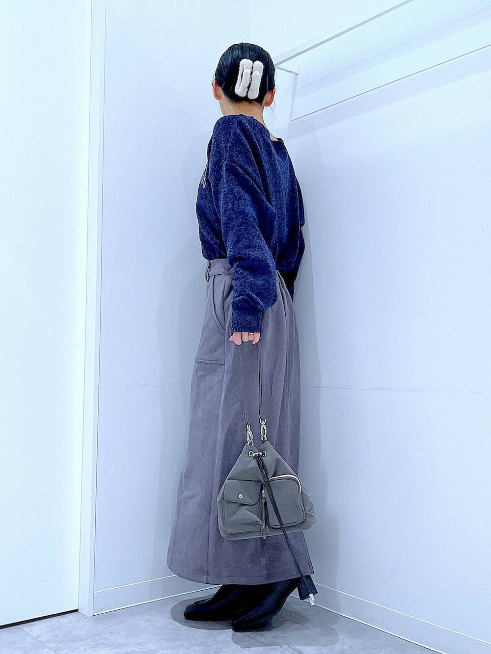 ブラック系のブーツ、ブルー系のニット/セーター、グレー系のスカートを着用したレディースの冬コーディネートの3枚目の写真