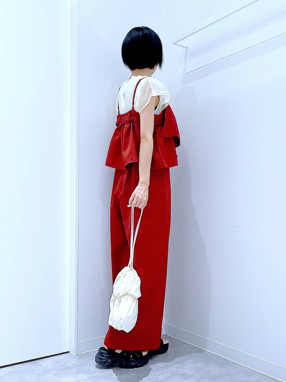 ブラック系のスニーカー、ホワイト系のショルダーバッグ、レッド系のつなぎ/オールインワンを着用したレディースの夏コーディネートの4枚目の写真