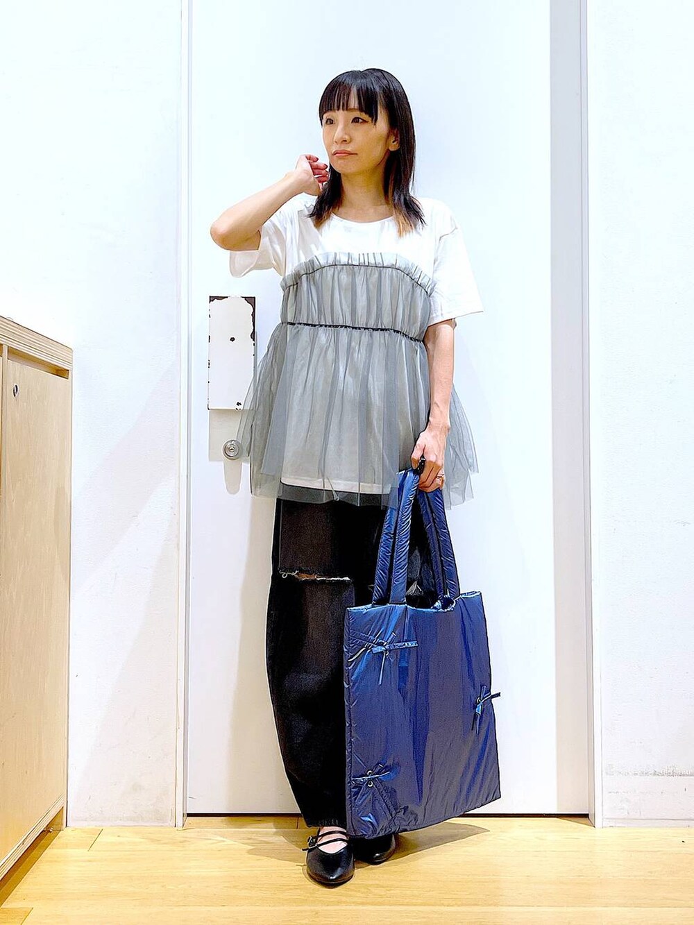 グレー系のTシャツ/カットソー、ブラック系のデニムパンツ、ブルー系のトートバッグを着用したレディースの秋コーディネートの2枚目の写真