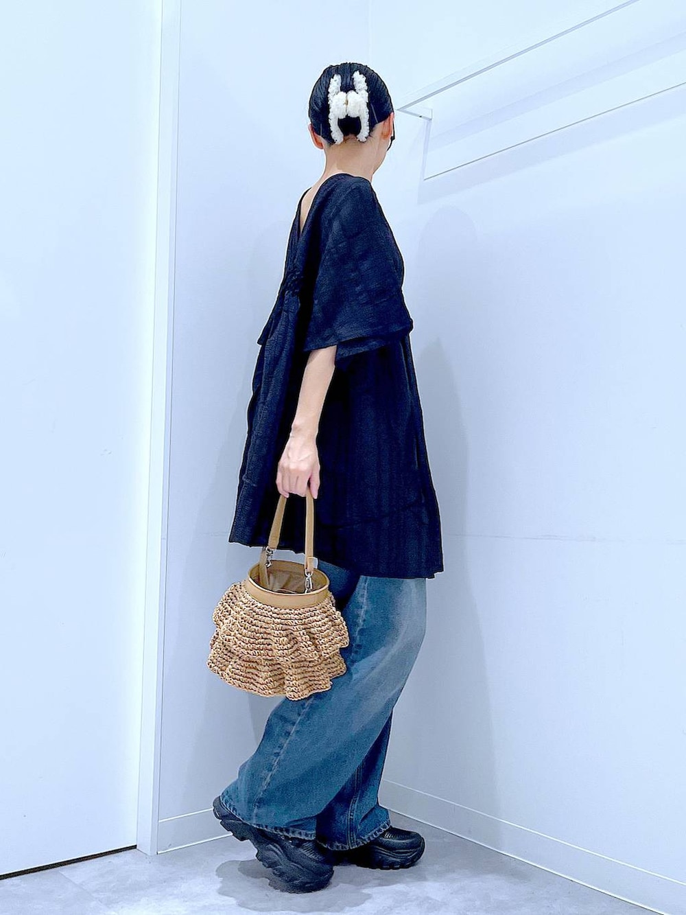 ブルー系のデニムパンツ、ブラック系のスニーカー、ベージュ系のショルダーバッグを着用したレディースの春コーディネートの4枚目の写真