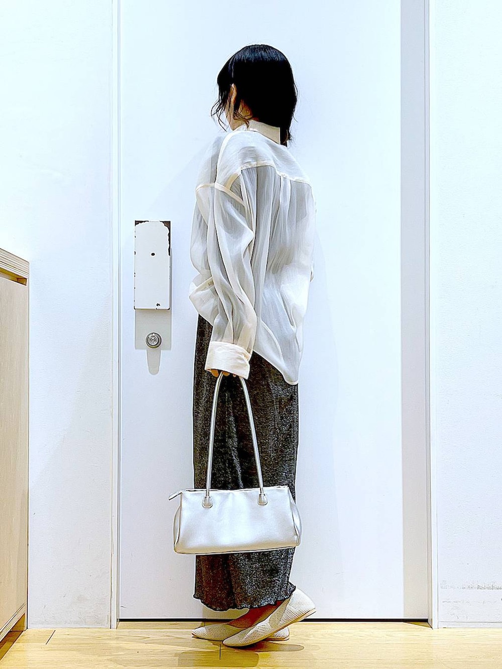 ブラック系のスカート、ホワイト系のパンプス、ホワイト系のシャツ/ブラウスを着用したレディースの春コーディネートの3枚目の写真