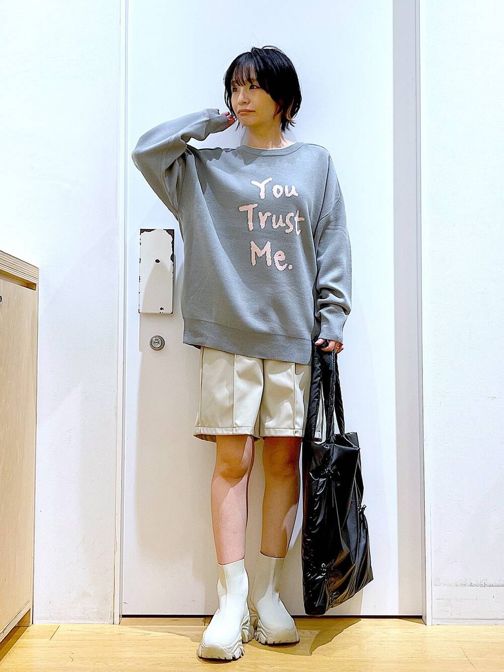 グレー系のニット/セーター、ブラック系のトートバッグ、ベージュ系のブーツを着用したレディースの冬コーディネートの2枚目の写真