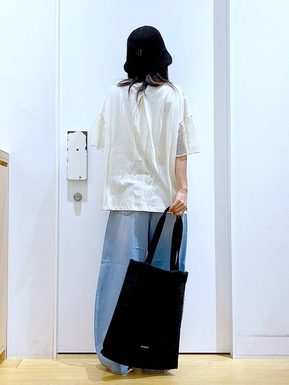 ブラック系のトートバッグ、ブルー系のデニムパンツ、シルバー系のパンプスを着用したレディースの夏コーディネートの5枚目の写真