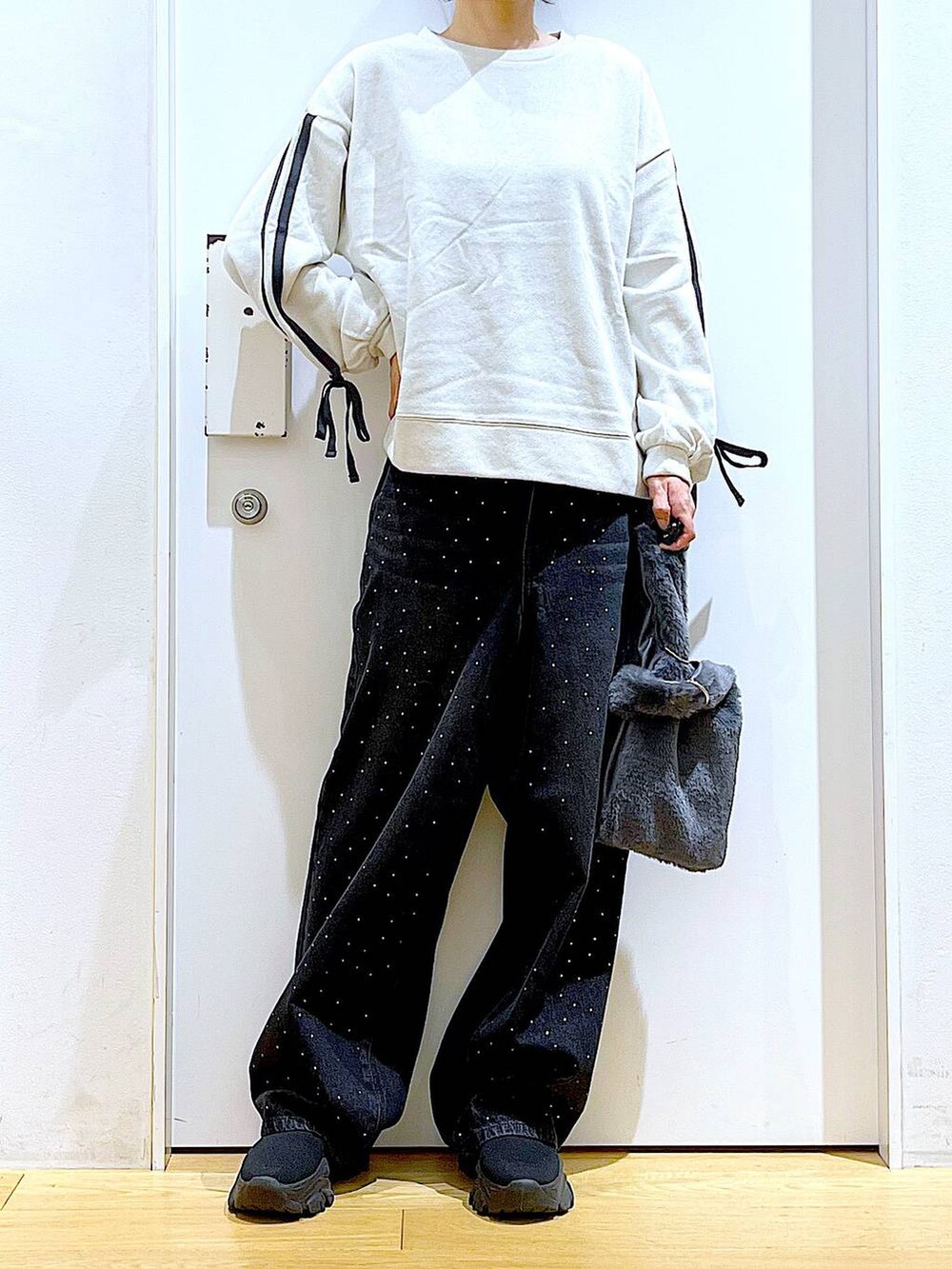 グレー系のショルダーバッグ、ブラック系のブーツ、ベージュ系のスウェットを着用したレディースの秋コーディネートの6枚目の写真