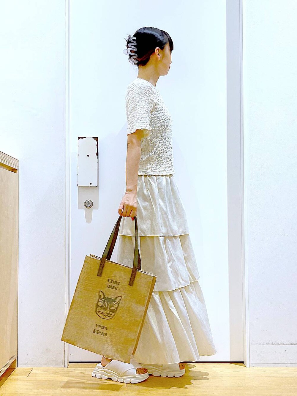 ホワイト系のサンダル、グレー系のトートバッグ、ゴールド系のスカートを着用したレディースの夏コーディネートの4枚目の写真