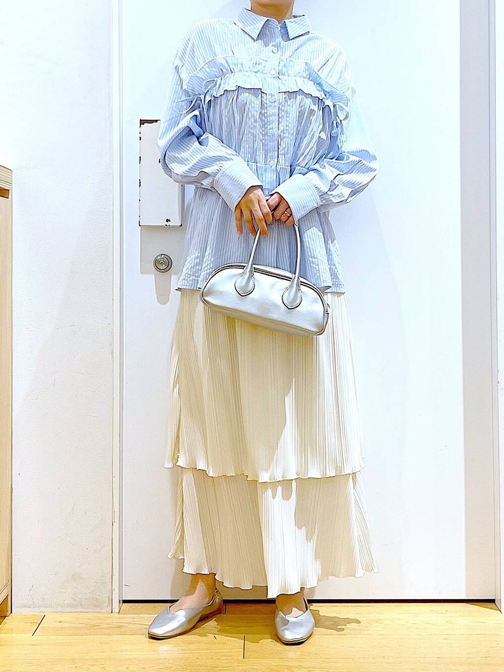 シルバー系のボストンバッグ、シルバー系のパンプス、ブルー系のシャツ/ブラウスを着用したレディースの春コーディネートの6枚目の写真