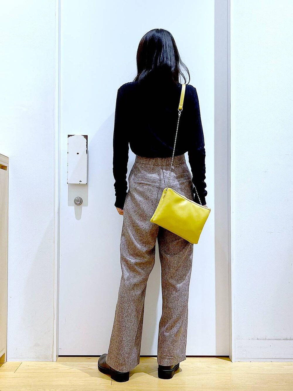 イエロー系のショルダーバッグ、ブラック系のブーツ、ブラウン系のその他パンツを着用したレディースの冬コーディネートの5枚目の写真