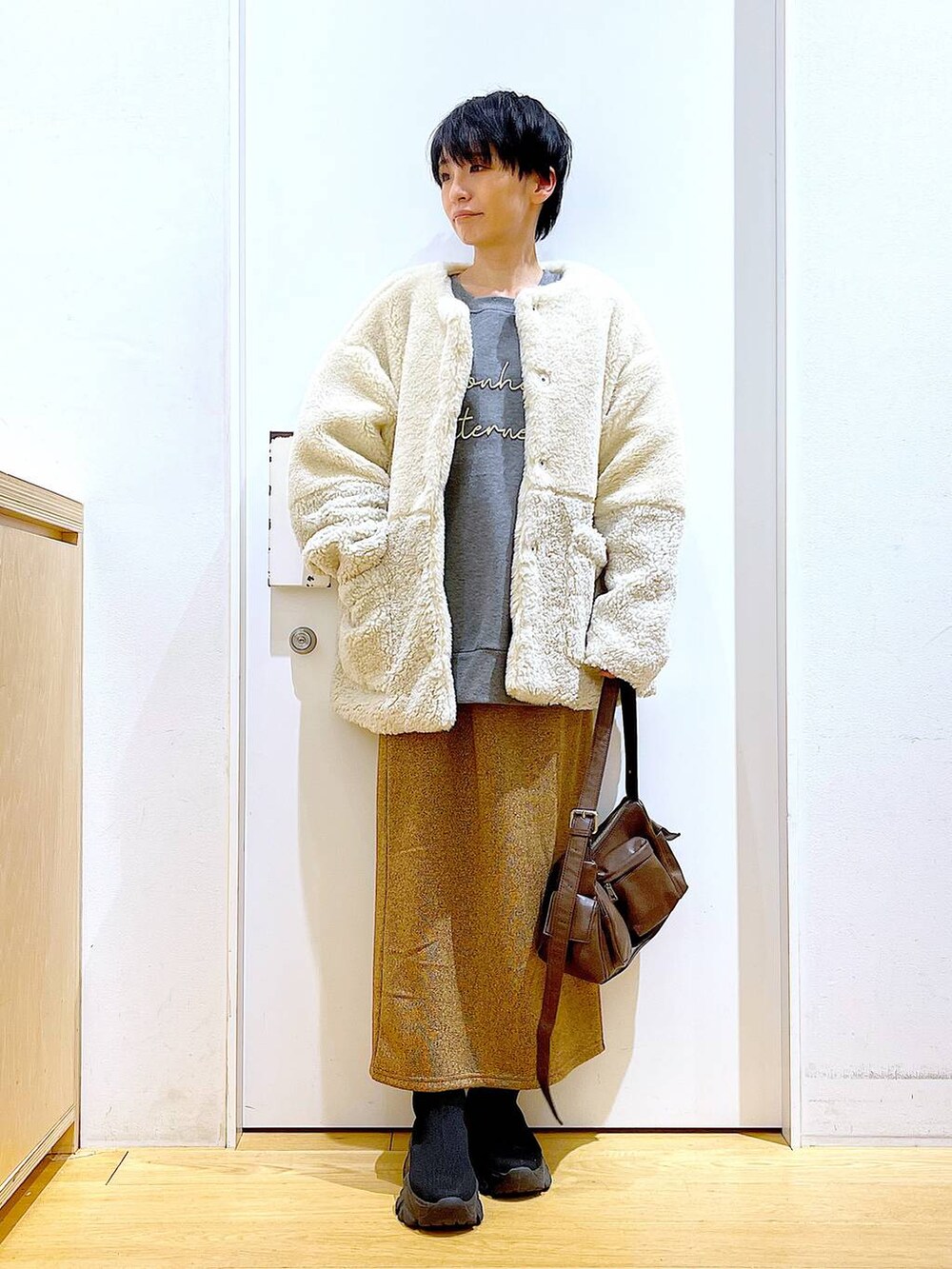 ベージュ系のブルゾン、ブラック系のブーツ、ブラウン系のショルダーバッグを着用したレディースの冬コーディネートの2枚目の写真