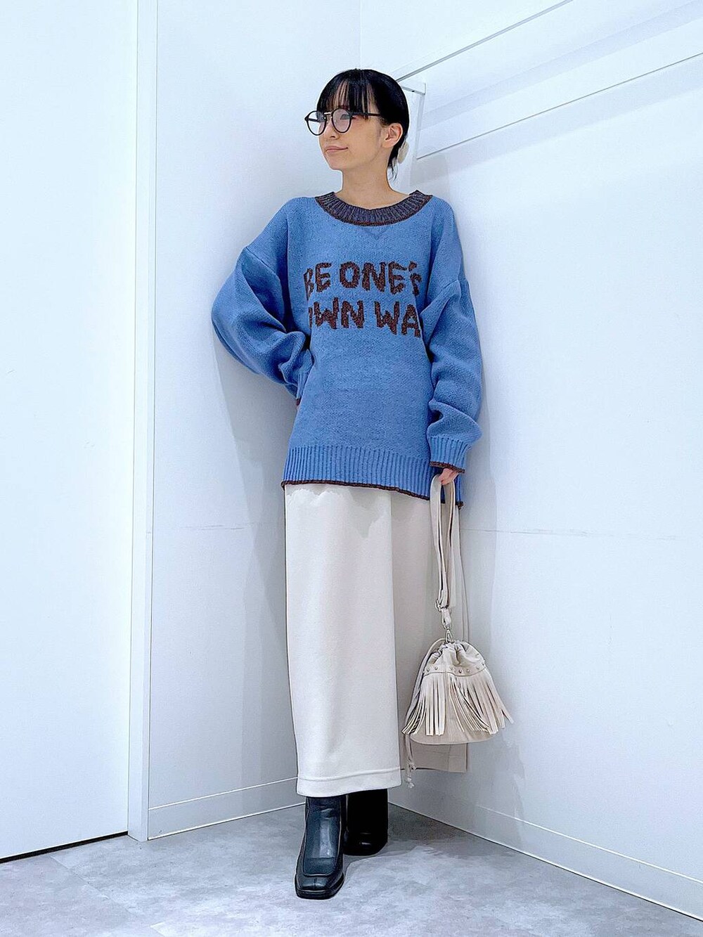 ベージュ系のスカート、ブラック系のブーツ、ホワイト系のショルダーバッグを着用したレディースの冬コーディネートの2枚目の写真