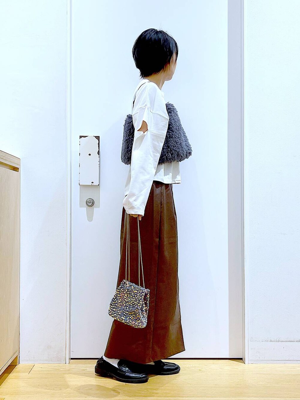 ブラウン系のスカート、グレー系のベスト、ブラック系のローファーを着用したレディースの秋コーディネートの4枚目の写真