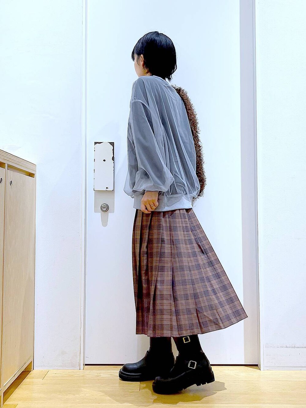 ブラック系のブーツ、ブラウン系のショルダーバッグ、ブラウン系のスカートを着用したレディースの秋コーディネートの3枚目の写真