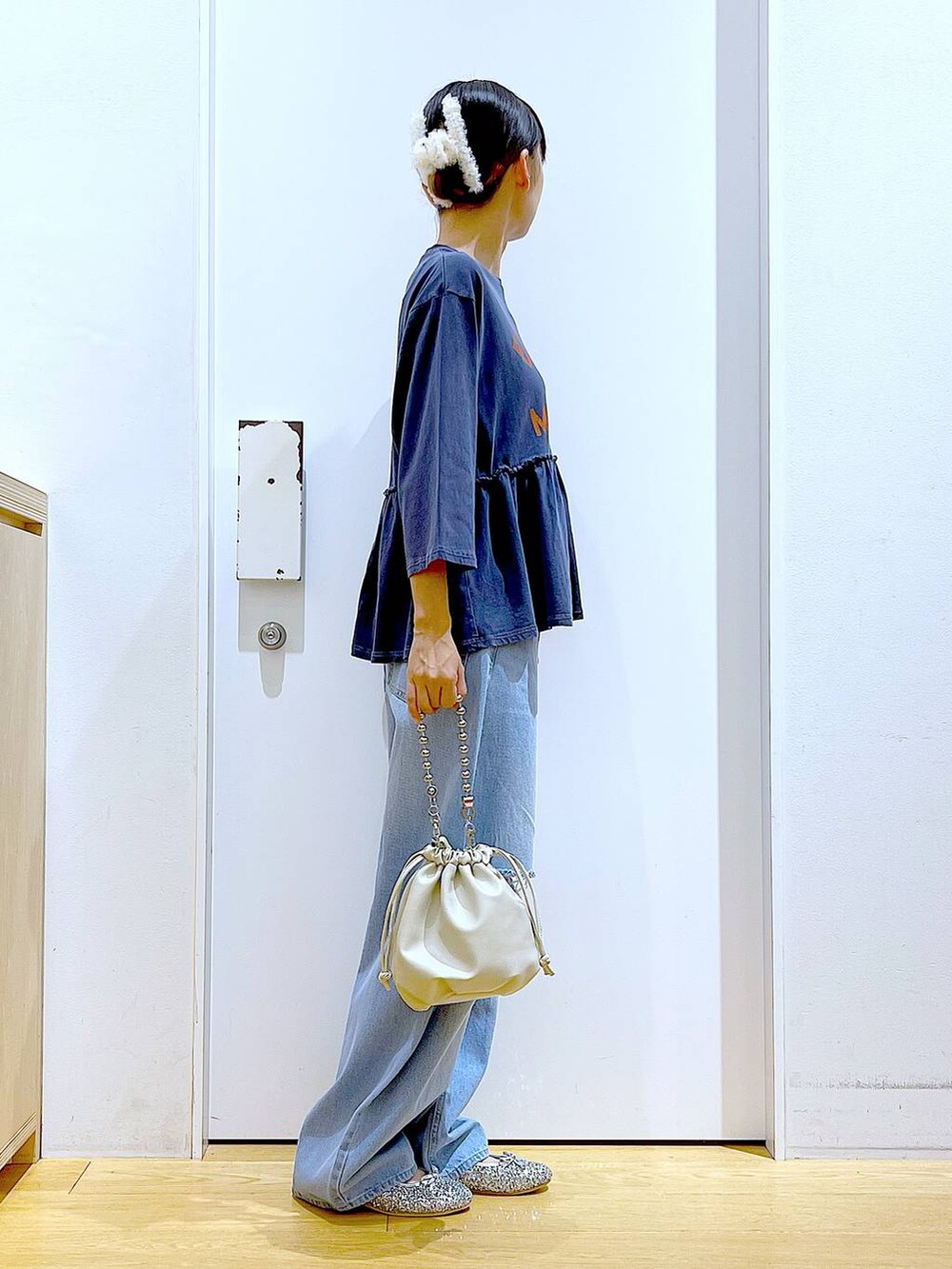 ブラック系のショルダーバッグ、ブルー系のデニムパンツ、シルバー系のパンプスを着用したレディースの秋コーディネートの4枚目の写真
