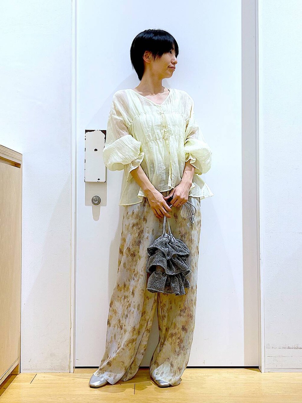 シルバー系のショルダーバッグ、シルバー系のパンプス、ベージュ系のシャツ/ブラウスを着用したレディースの夏コーディネートの2枚目の写真