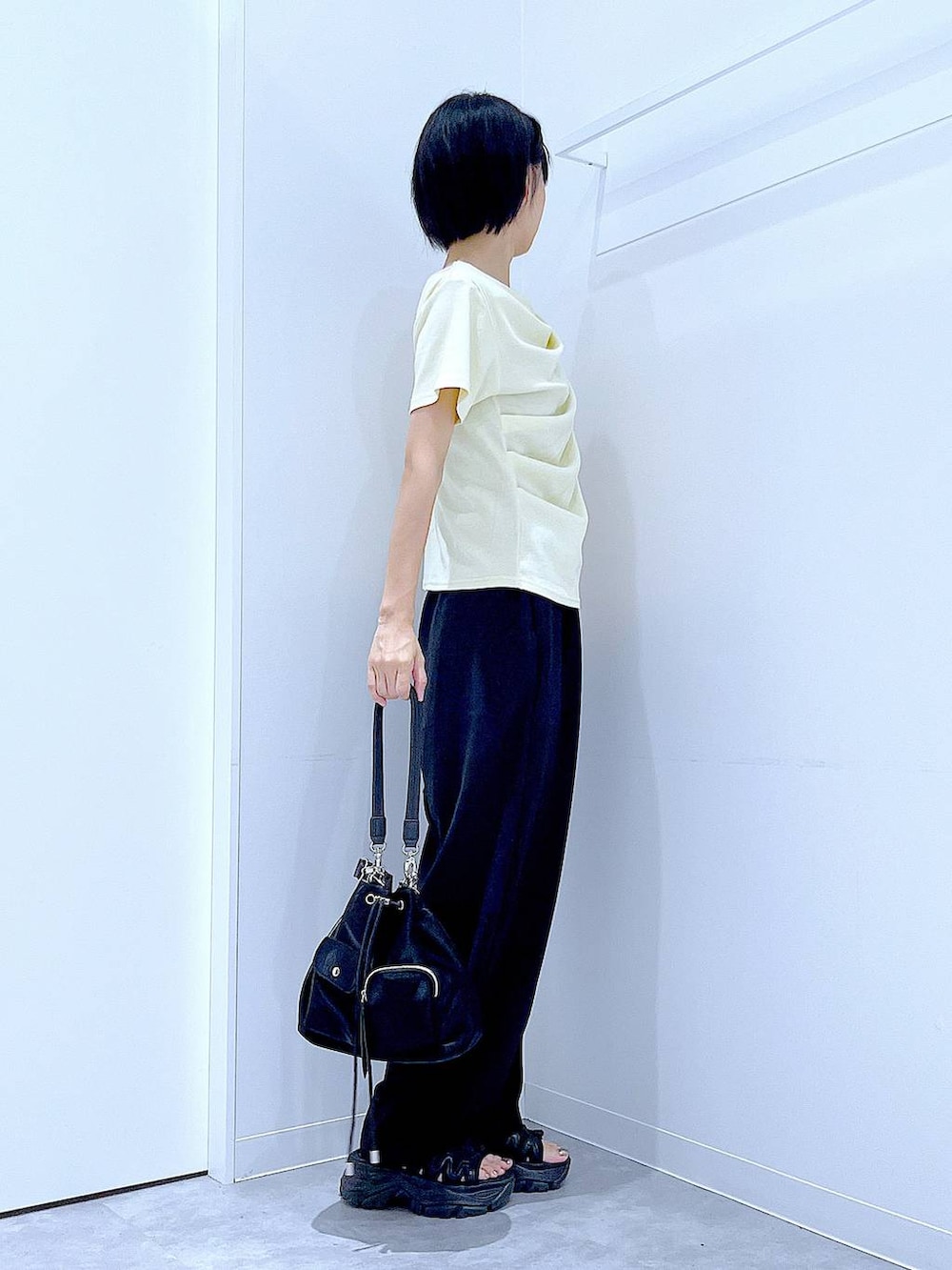 ブラック系のスニーカー、ブラック系のショルダーバッグ、イエロー系のTシャツ/カットソーを着用したレディースの夏コーディネートの4枚目の写真