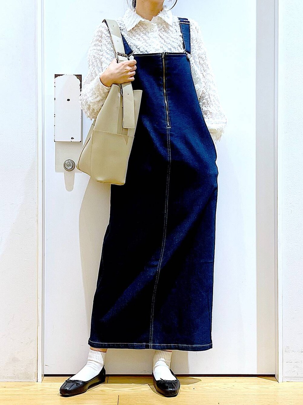 グレー系のショルダーバッグ、ブラック系のバレエシューズ、ブルー系のジャンパースカートを着用したレディースの春コーディネートの6枚目の写真