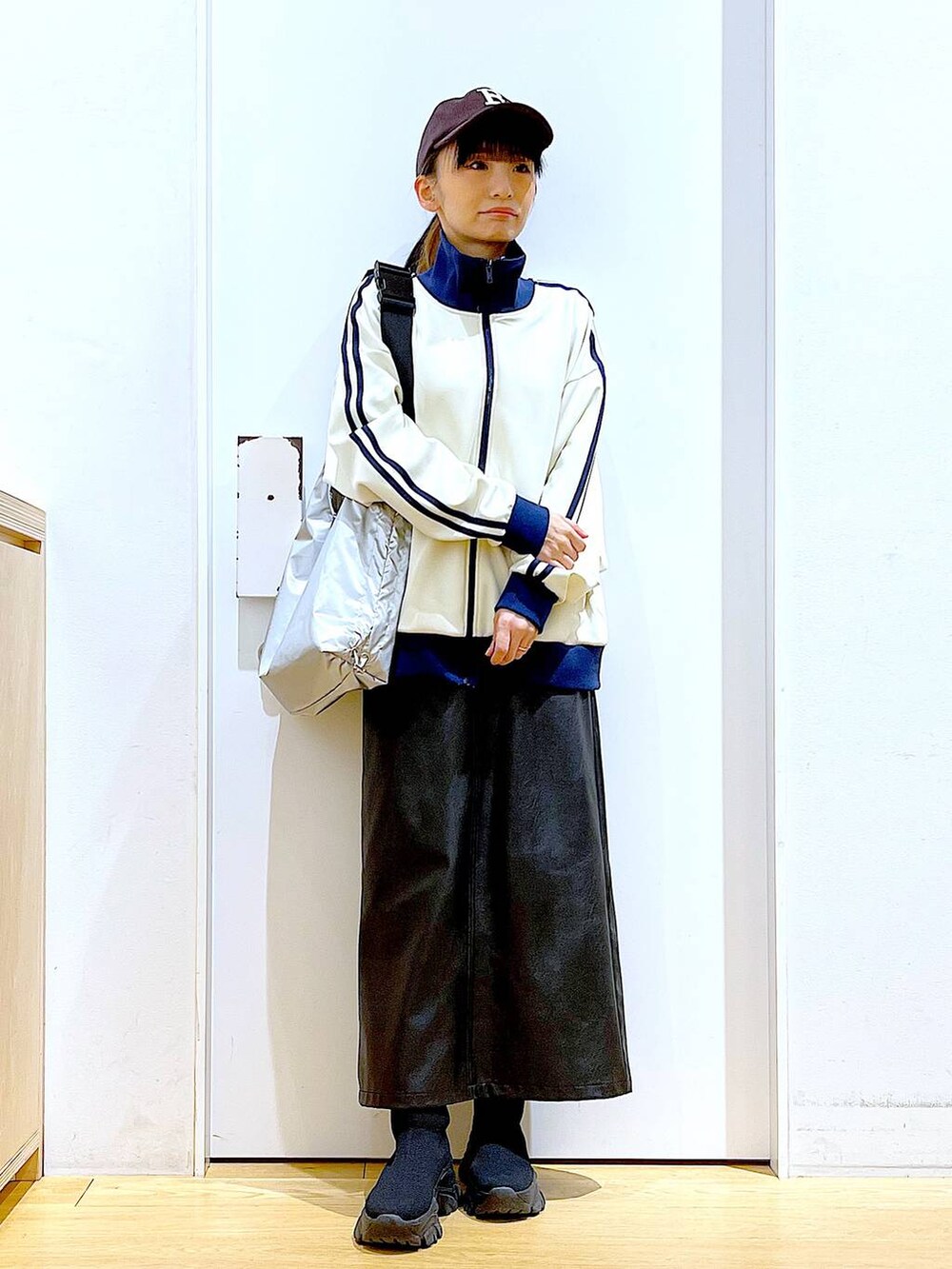 ブラック系のブーツ、ブラック系のスカート、シルバー系のショルダーバッグを着用したレディースの冬コーディネートの2枚目の写真