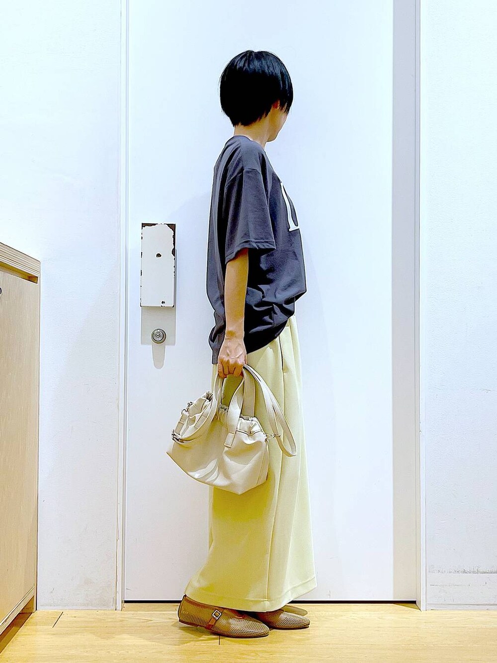 ホワイト系のショルダーバッグ、ベージュ系のパンプス、イエロー系のスカートを着用したレディースの夏コーディネートの4枚目の写真