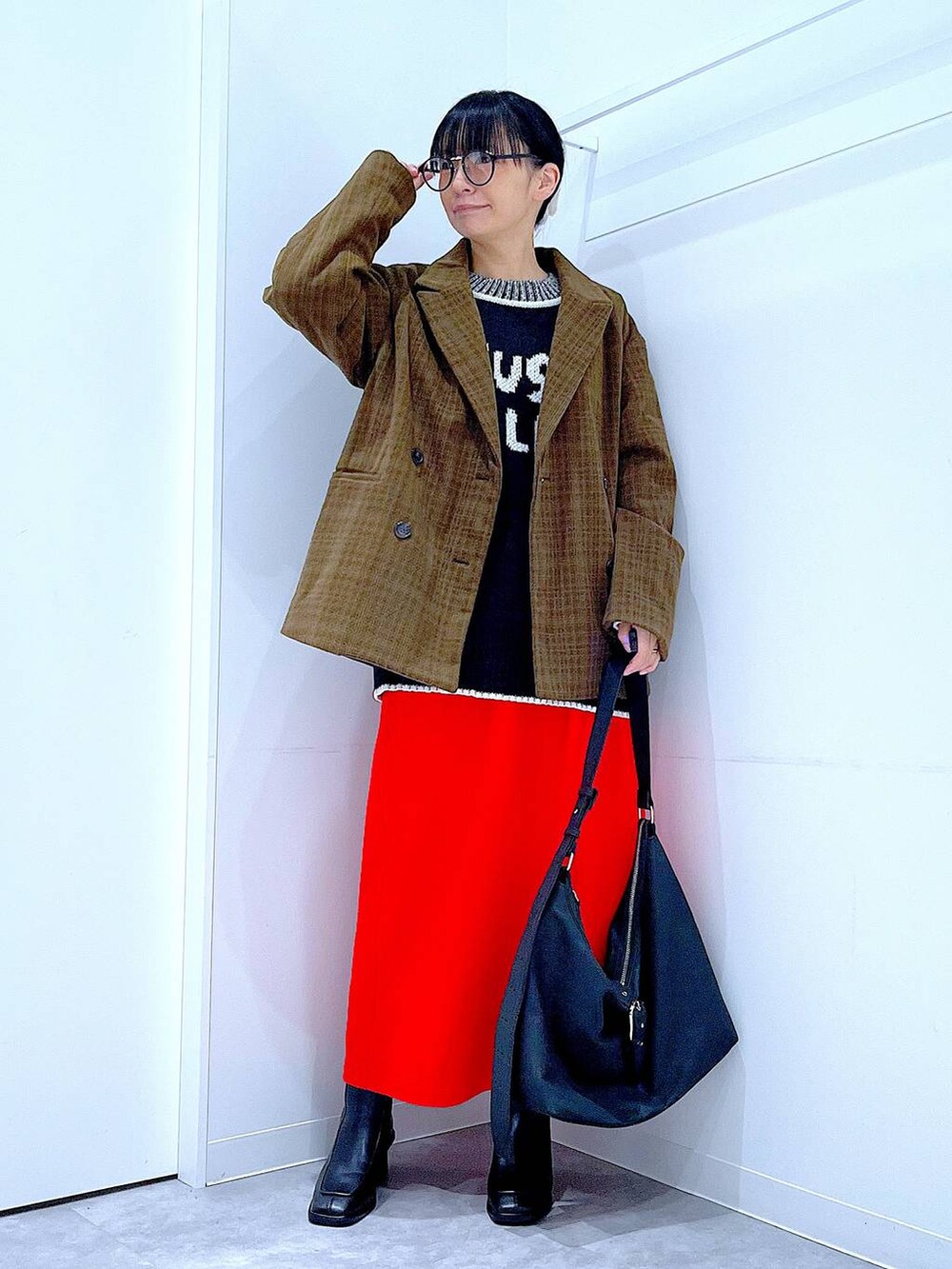 レッド系のスカート、ブラック系のブーツ、ブラック系のショルダーバッグを着用したレディースの冬コーディネートの2枚目の写真