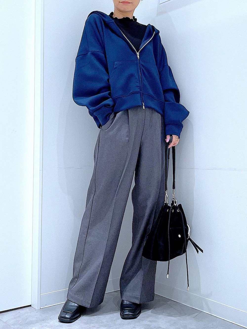 ブラック系のショルダーバッグ、ブラック系のブーツ、グレー系のスラックスを着用したレディースの冬コーディネートの6枚目の写真