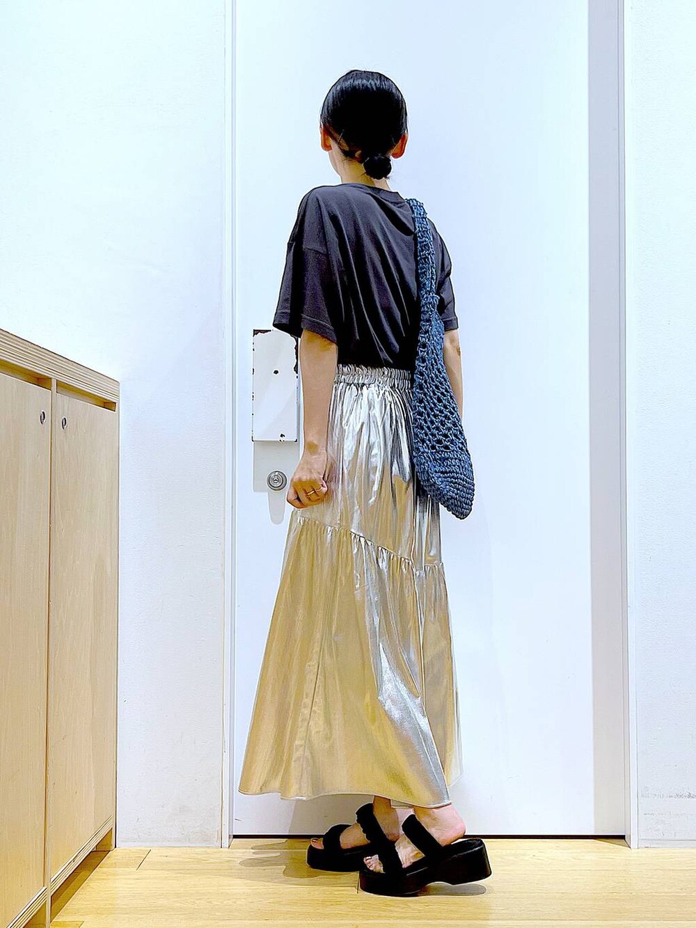 ブラック系のサンダル、シルバー系のスカート、ブルー系のトートバッグを着用したレディースの夏コーディネートの3枚目の写真