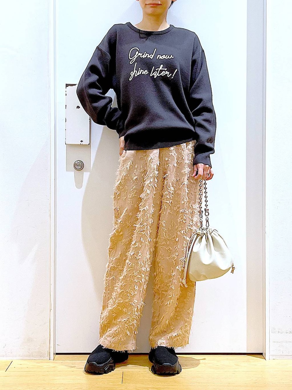 ベージュ系のショルダーバッグ、ブラック系のブーツ、グレー系のニット/セーターを着用したレディースの春コーディネートの6枚目の写真