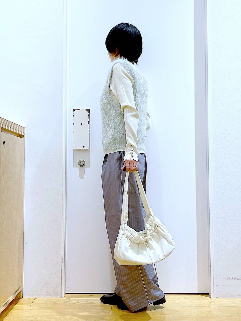 ホワイト系のニット/セーター、ホワイト系のハンドバッグ、グレー系のスラックスを着用したレディースの秋コーディネートの3枚目の写真