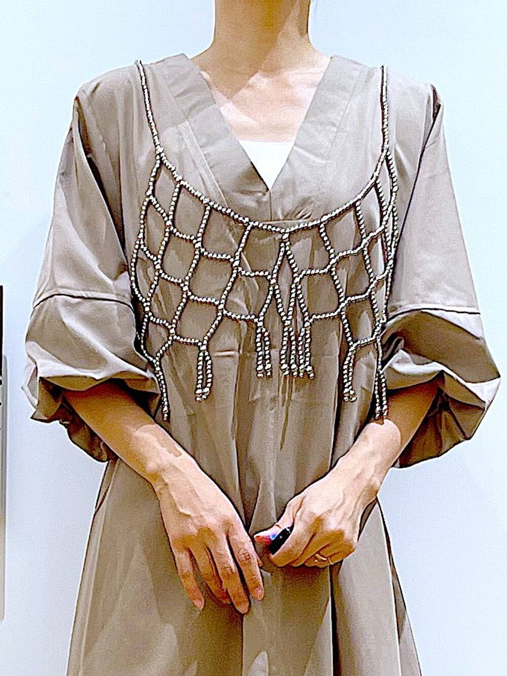 ブラック系のトートバッグ、ベージュ系のワンピース、シルバー系のパンプスを着用したレディースの夏コーディネートの7枚目の写真