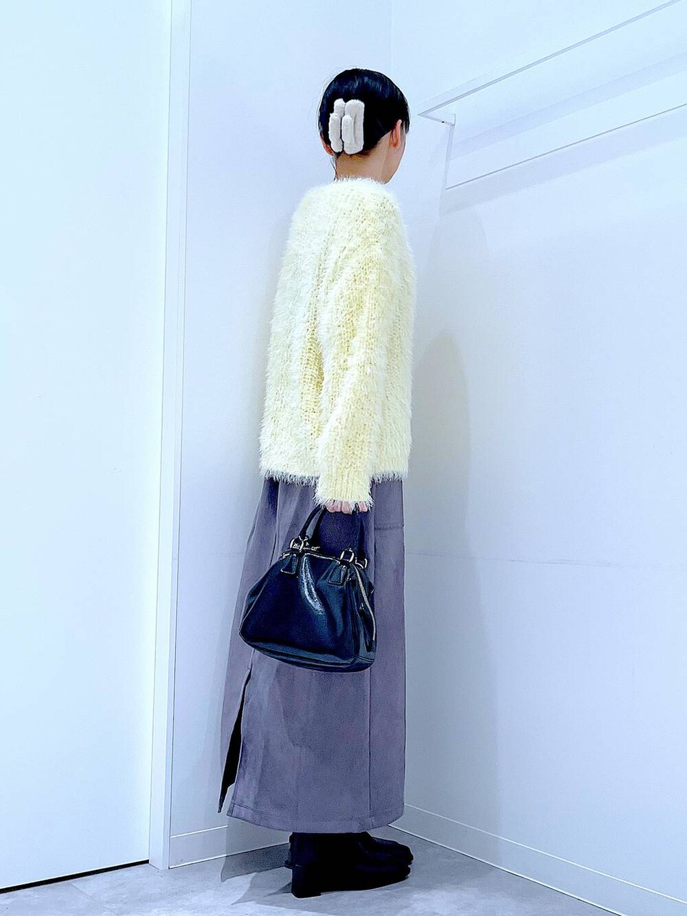 ブラック系のブーツ、イエロー系のニット/セーター、ブラック系のショルダーバッグを着用したレディースの冬コーディネートの4枚目の写真