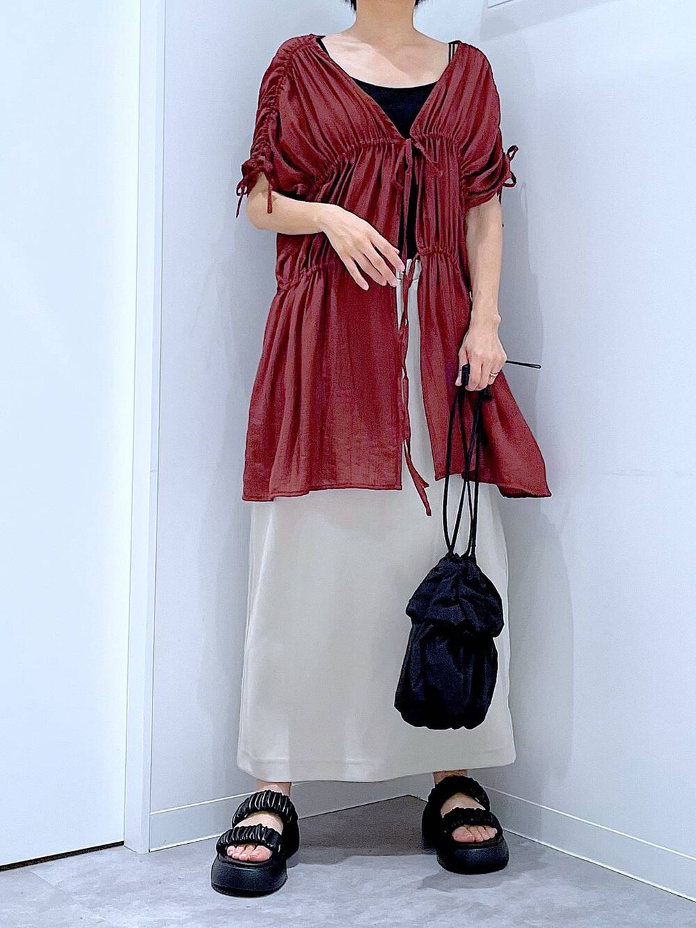 ブラック系のサンダル、ベージュ系のスカート、ブラック系のショルダーバッグを着用したレディースの秋コーディネートの6枚目の写真