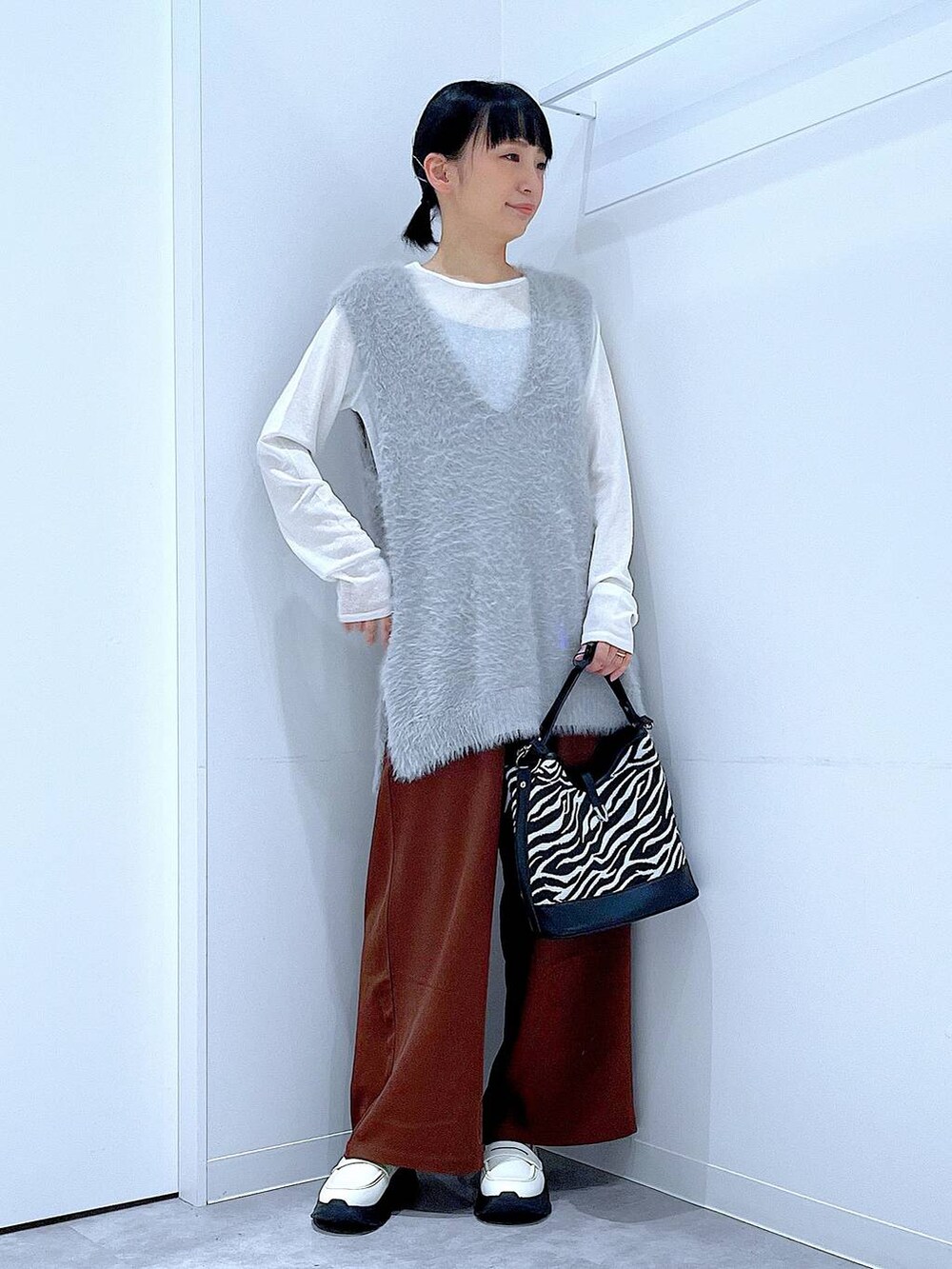ホワイト系のTシャツ/カットソー、ホワイト系のローファー、グレー系のベストを着用したレディースの秋コーディネートの2枚目の写真