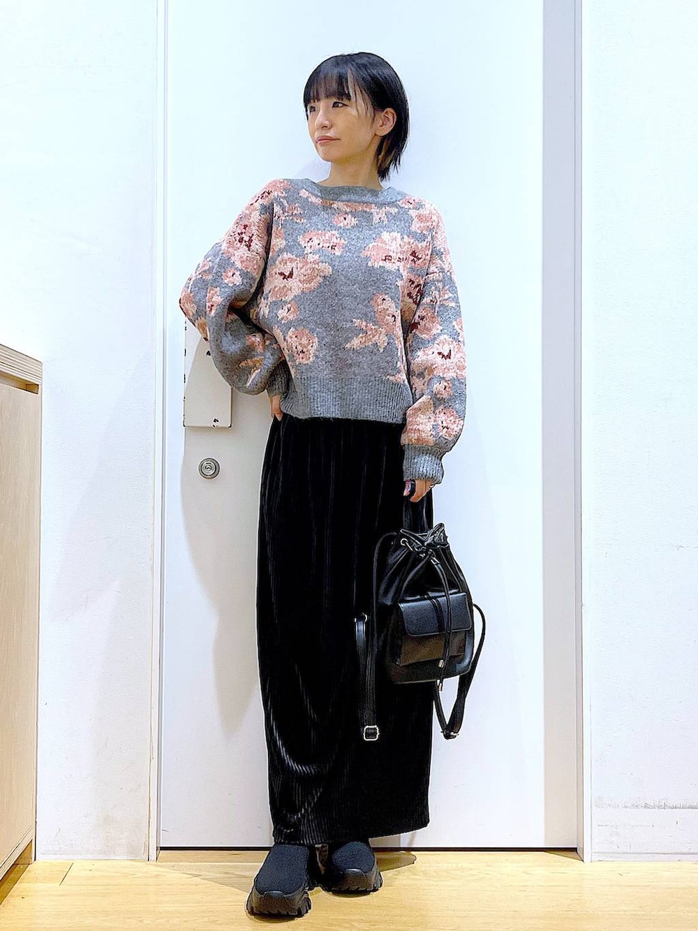 ブラック系のバックパック/リュック、ブラック系のスカート、ブラック系のブーツを着用したレディースの秋コーディネートの2枚目の写真