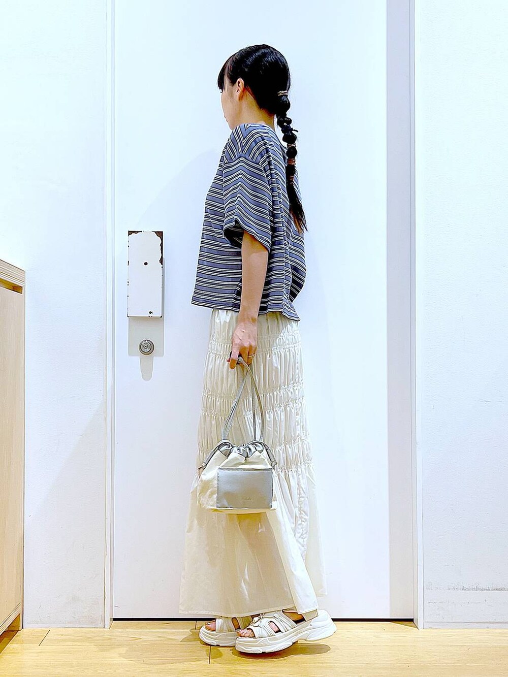 ホワイト系のショルダーバッグ、ホワイト系のサンダル、グレー系のTシャツ/カットソーを着用したレディースの夏コーディネートの3枚目の写真