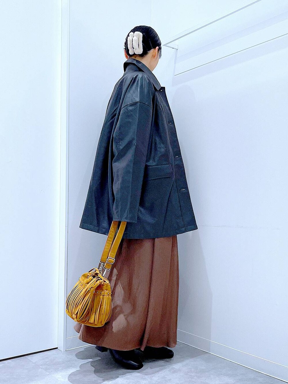 ブラック系のステンカラーコート、レッド系のニット/セーター、ブラック系のブーツを着用したレディースの冬コーディネートの4枚目の写真