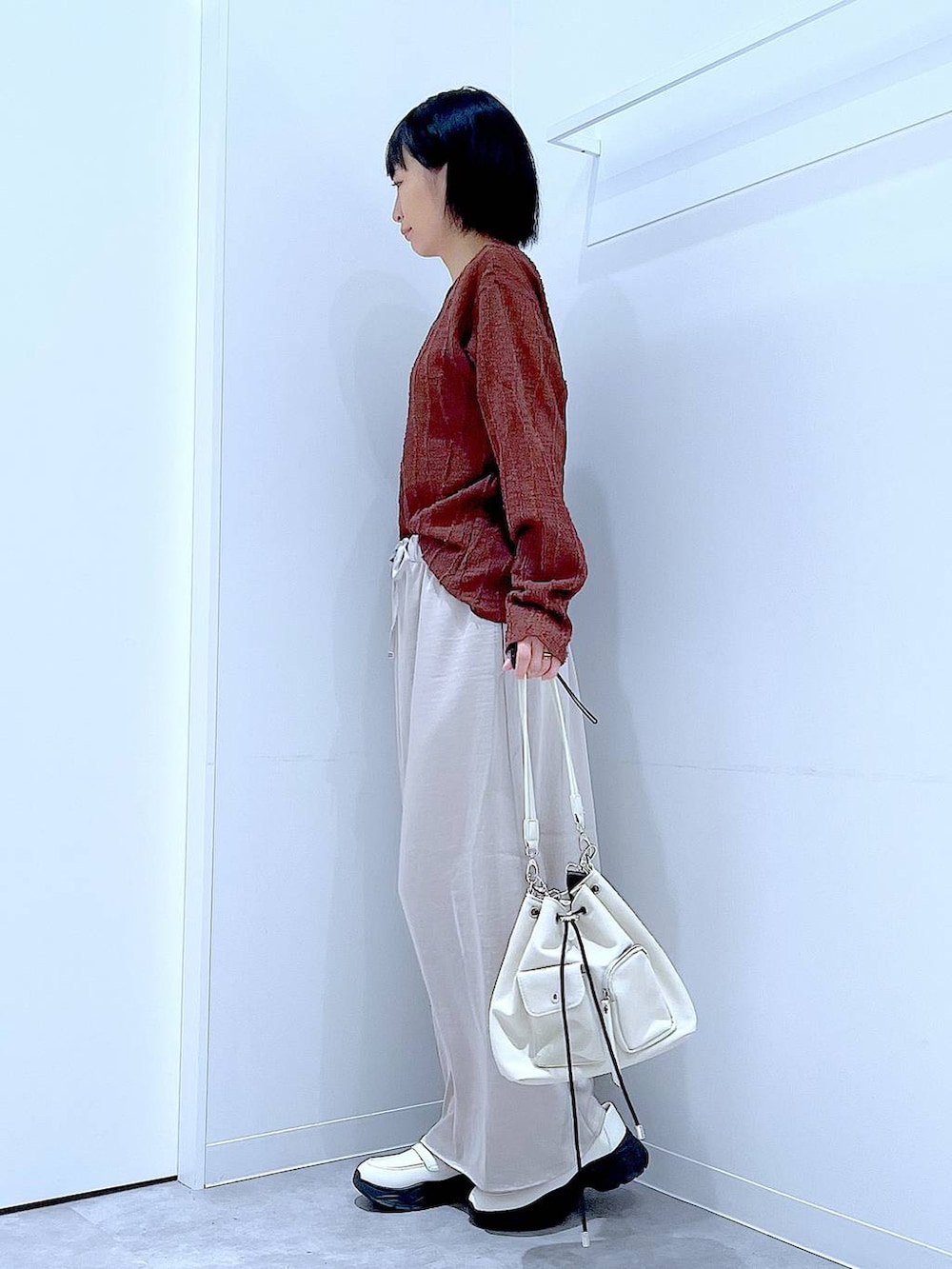 ホワイト系のローファー、ホワイト系のショルダーバッグ、ベージュ系のスカートを着用したレディースの秋コーディネートの3枚目の写真