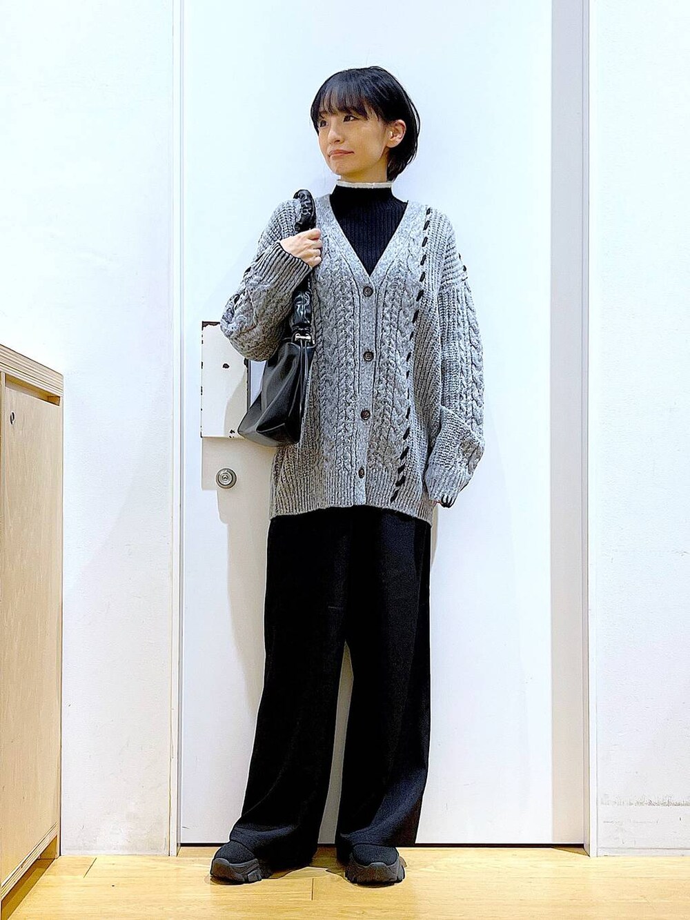 ブラック系のニット/セーター、ブラック系のブーツ、ブラック系のショルダーバッグを着用したレディースの冬コーディネートの2枚目の写真