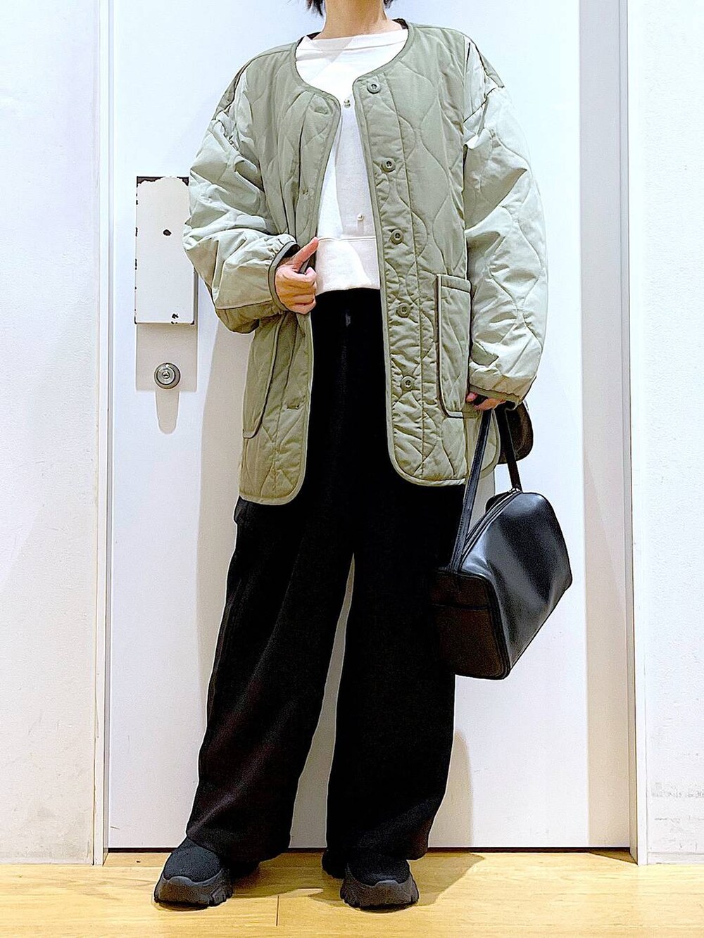 ブラック系のショルダーバッグ、ホワイト系のスウェット、ブラック系のブーツを着用したレディースの秋コーディネートの6枚目の写真