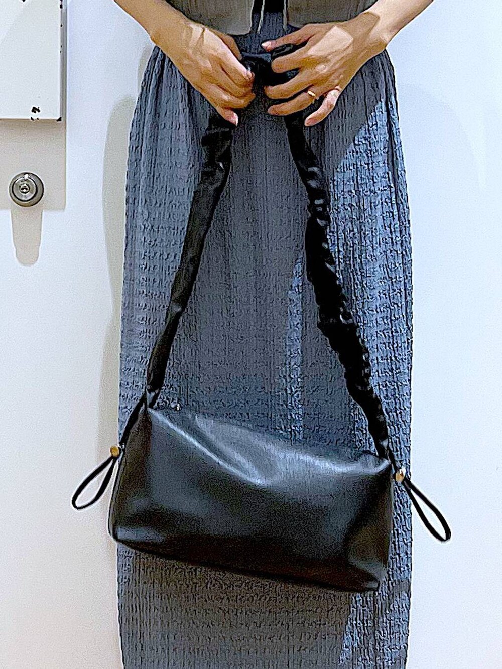 ブラック系のショルダーバッグ、ブルー系のスカート、ブラック系のTシャツ/カットソーを着用したレディースの夏コーディネートの9枚目の写真