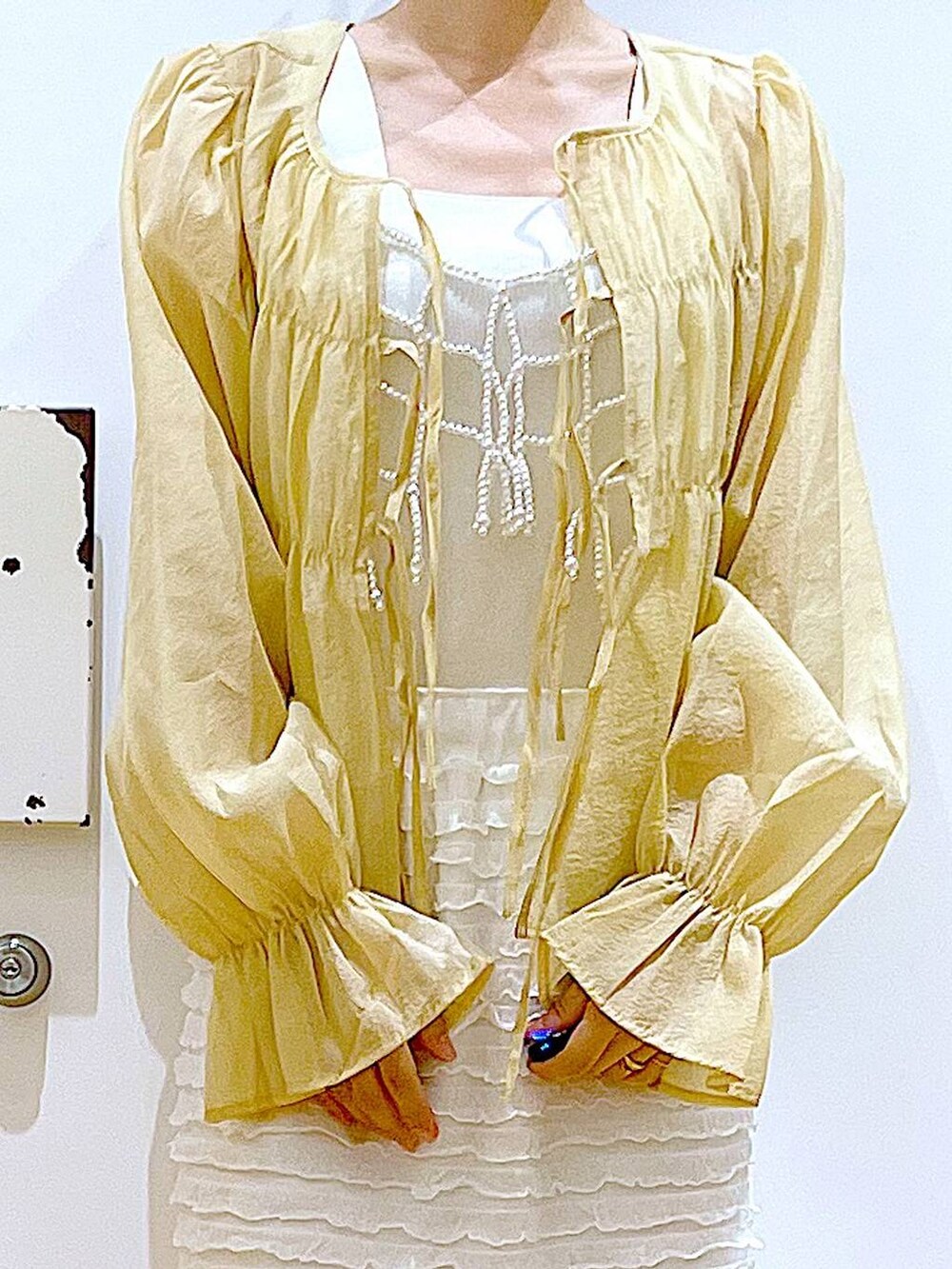 ホワイト系のベスト、ホワイト系のショルダーバッグ、ホワイト系のスカートを着用したレディースの秋コーディネートの7枚目の写真