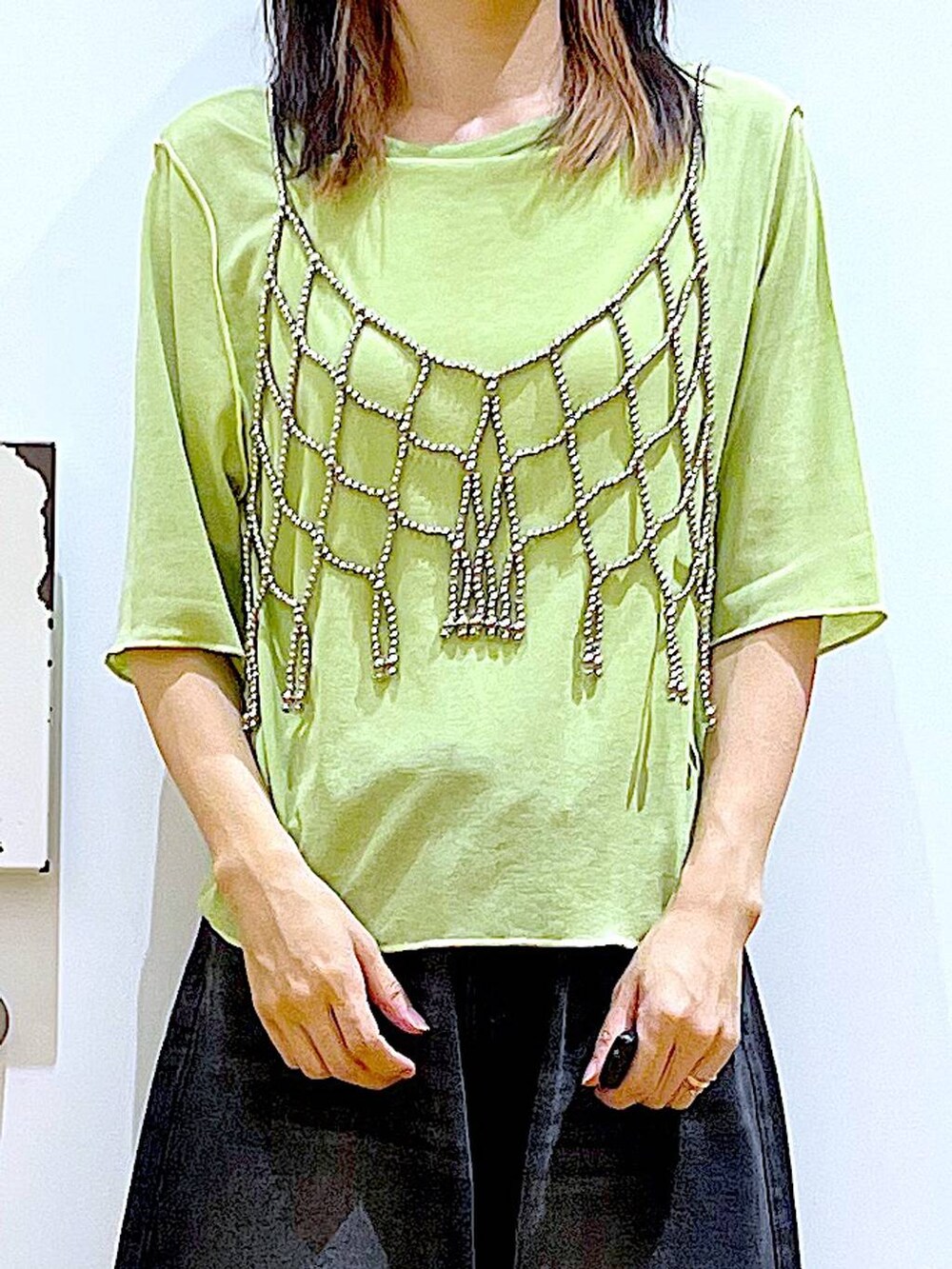 グリーン系のTシャツ/カットソー、ブラック系のデニムパンツ、ブラック系のパンプスを着用したレディースの秋コーディネートの7枚目の写真