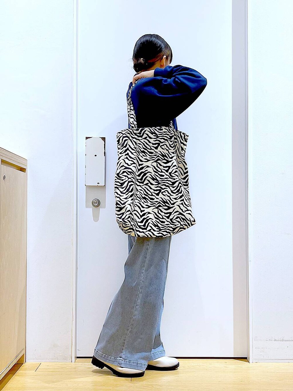 ブルー系のデニムパンツ、ブルー系のスウェット、ベージュ系のブーツを着用したレディースの春コーディネートの4枚目の写真