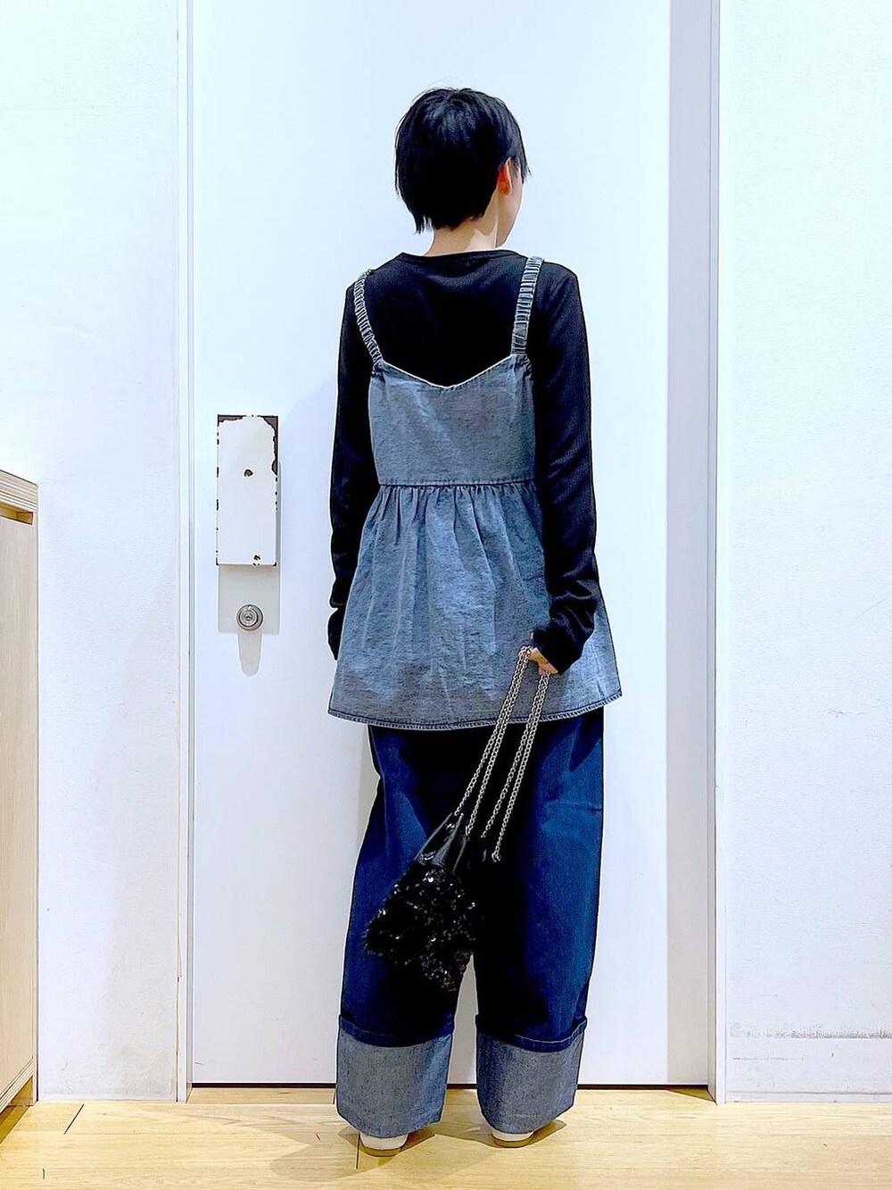 ホワイト系のパンプス、ブルー系のデニムパンツ、ブラック系のショルダーバッグを着用したレディースの春コーディネートの5枚目の写真