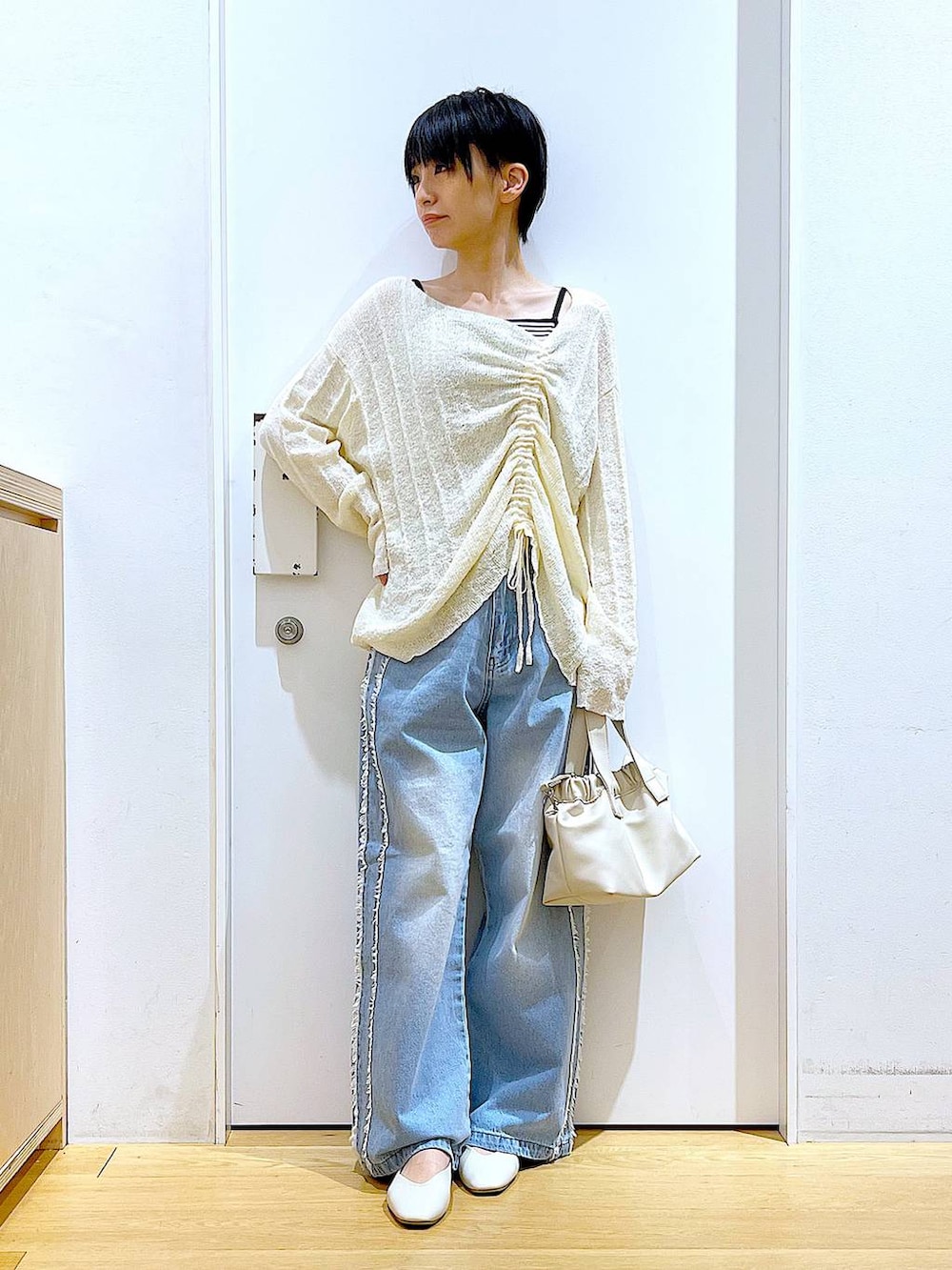 ホワイト系のショルダーバッグ、ホワイト系のパンプス、ブルー系のデニムパンツを着用したレディースの春コーディネートの2枚目の写真