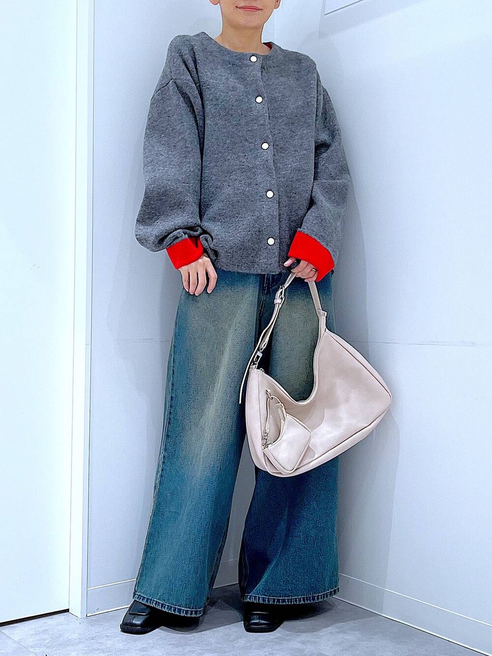 ブルー系のデニムパンツ、ブラック系のブーツ、ホワイト系のショルダーバッグを着用したレディースの冬コーディネートの6枚目の写真