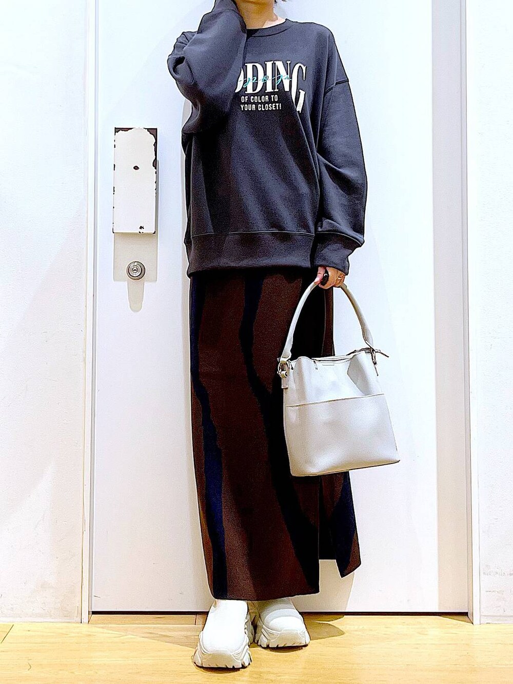 ブラウン系のスカート、グレー系のショルダーバッグ、ベージュ系のブーツを着用したレディースの冬コーディネートの6枚目の写真