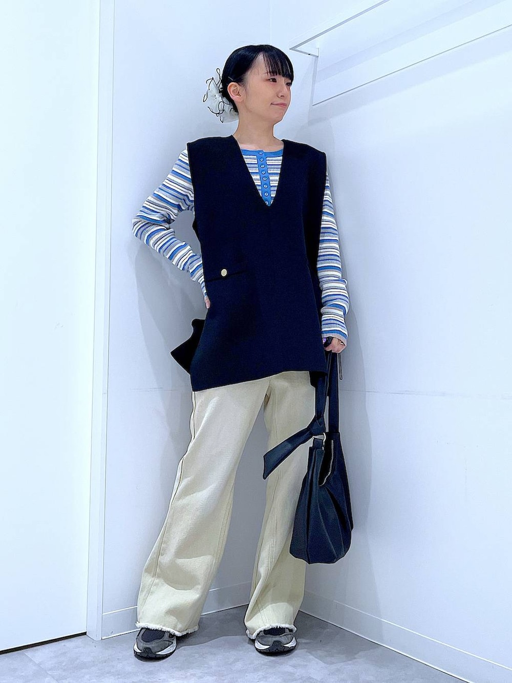 ブルー系のニット/セーター、ブラック系のベスト、ベージュ系のデニムパンツを着用したレディースの冬コーディネートの2枚目の写真