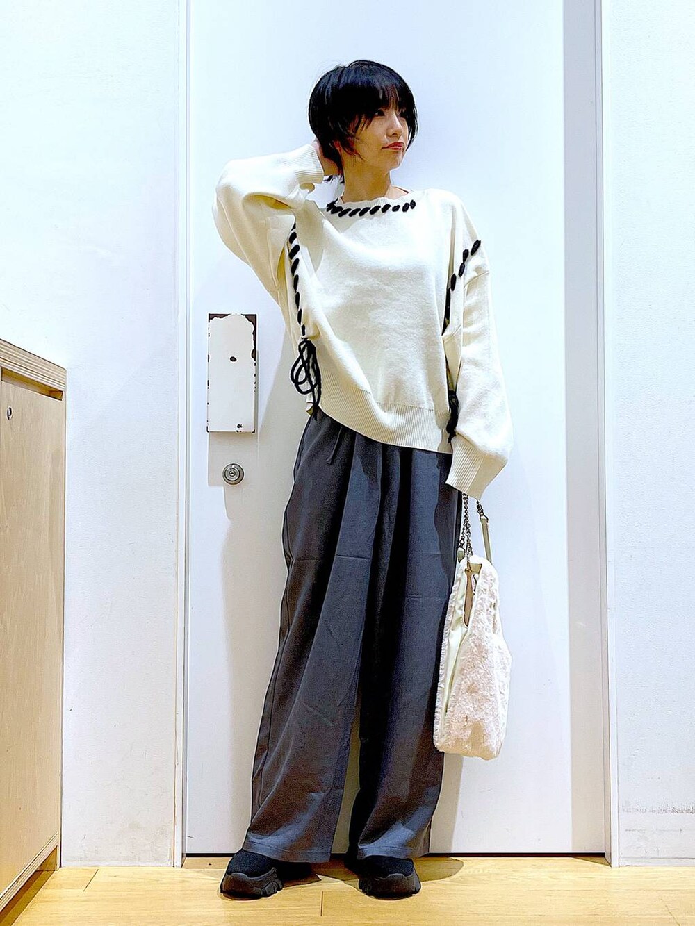 ホワイト系のショルダーバッグ、ブラック系のブーツ、グレー系のその他パンツを着用したレディースの冬コーディネートの2枚目の写真