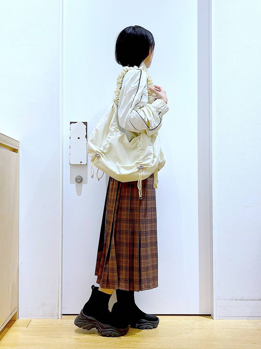 ホワイト系のショルダーバッグ、ベージュ系のブルゾン、ブラック系のブーツを着用したレディースの秋コーディネートの4枚目の写真